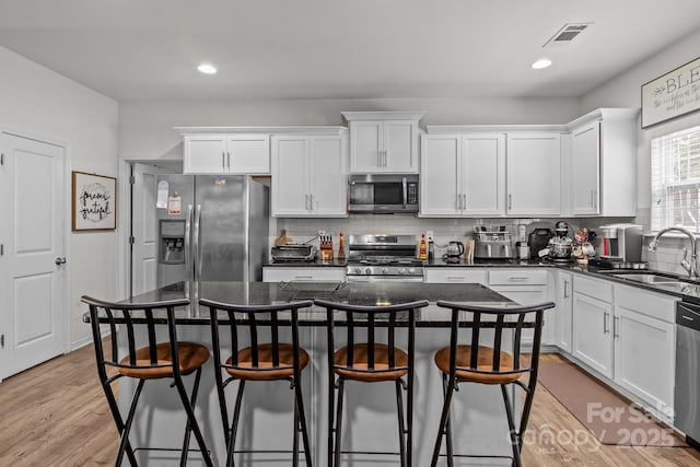 413 Wheat Field Dr, Mount Holly, NC 28120 - kitchen featuring stainless steel appliances, a sink, a breakfast bar area, white cabinets, and recessed lighting
