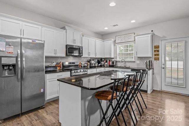 413 Wheat Field Dr, Mount Holly, NC 28120 - kitchen featuring stainless steel appliances, wood finished floors, white cabinets, a kitchen breakfast bar, and recessed lighting