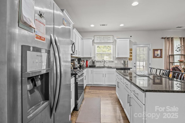 413 Wheat Field Dr, Mount Holly, NC 28120 - kitchen with stainless steel appliances, a sink, dark wood finished floors, white cabinetry, and a kitchen island