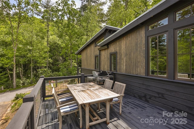 wooden deck with outdoor dining area and area for grilling
