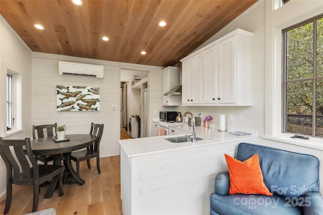 kitchen featuring a wall mounted air conditioner, a sink, washer / clothes dryer, wooden walls, and wooden ceiling