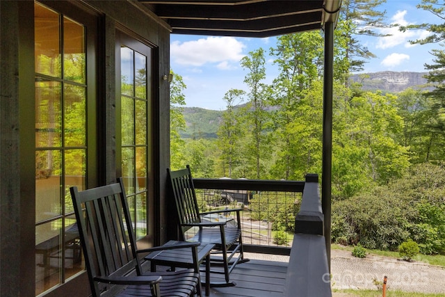 wooden terrace featuring a mountain view and a view of trees