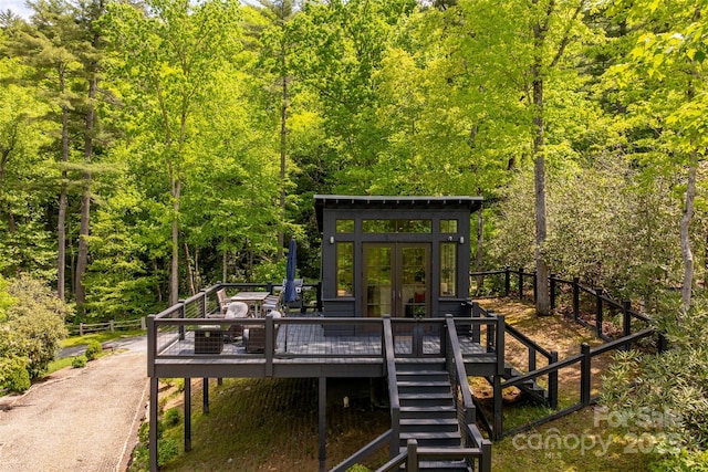 deck featuring a view of trees, french doors, and stairway