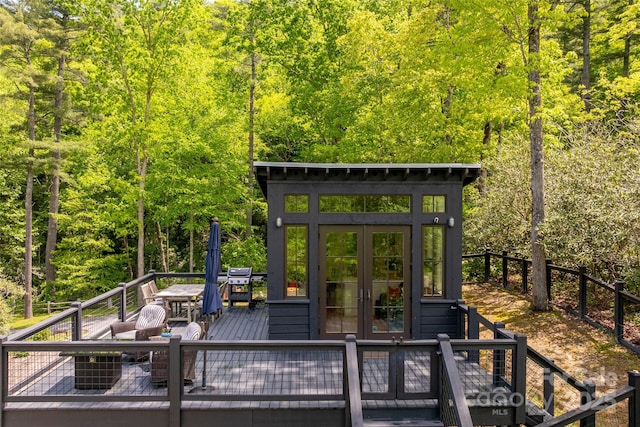 wooden terrace with french doors and a view of trees