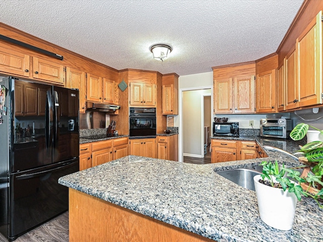 202 Cameron Dr, Kings Mountain, NC 28086 - kitchen with black appliances, under cabinet range hood, a sink, a textured ceiling, and dark stone counters