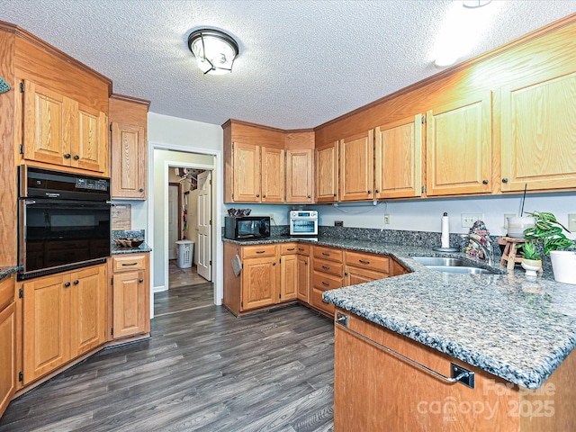 202 Cameron Dr, Kings Mountain, NC 28086 - kitchen with black appliances, dark wood-style floors, a textured ceiling, dark stone counters, and a sink