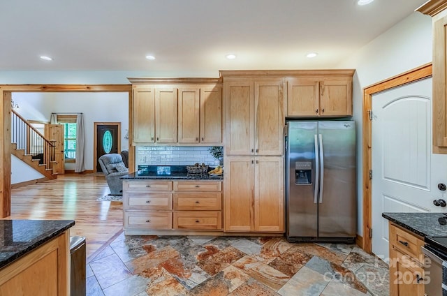 kitchen featuring stainless steel fridge with ice dispenser, dark stone countertops, decorative backsplash, and recessed lighting