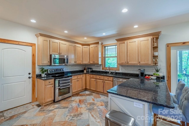 kitchen featuring appliances with stainless steel finishes, a sink, light brown cabinets, and recessed lighting