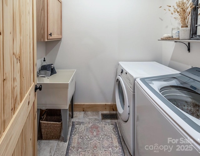 washroom featuring washing machine and clothes dryer, cabinet space, and baseboards