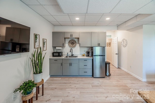 kitchen with black appliances, a sink, gray cabinetry, recessed lighting, and light wood-type flooring