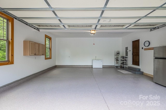 garage featuring freestanding refrigerator, baseboards, and a garage door opener