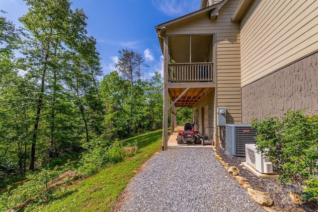 view of side of property with central AC, a patio area, a cooling unit, and gravel driveway
