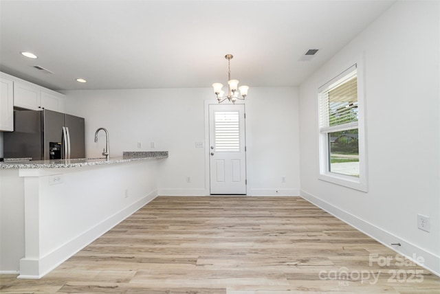 kitchen with stainless steel fridge with ice dispenser, a sink, a chandelier, white cabinetry, and recessed lighting