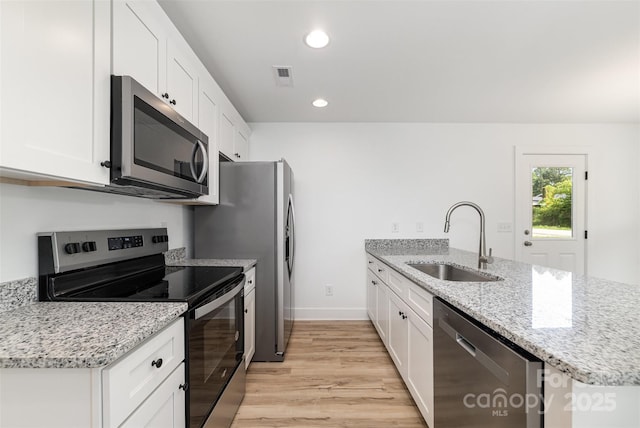 kitchen with appliances with stainless steel finishes, a sink, a peninsula, white cabinets, and recessed lighting