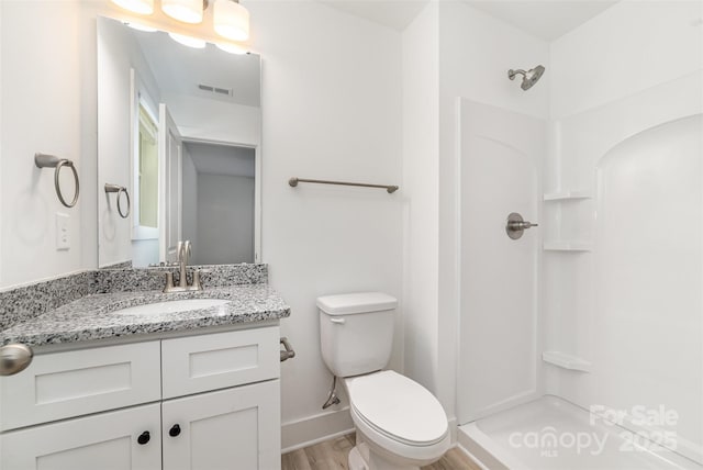 bathroom with toilet, a shower, vanity, and wood finished floors