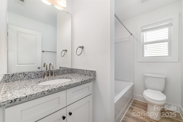 bathroom with toilet, baseboards, vanity, wood finished floors, and washtub / shower combination
