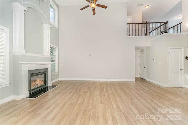 140 Wintergreen Ct, Lexington, NC 27295 - unfurnished living room featuring a high ceiling, a ceiling fan, a glass covered fireplace, wood finished floors, and baseboards