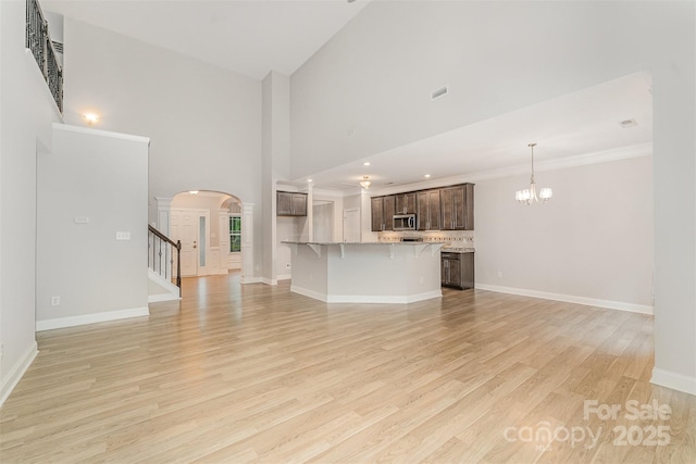 140 Wintergreen Ct, Lexington, NC 27295 - unfurnished living room with arched walkways, light wood finished floors, stairway, a chandelier, and baseboards