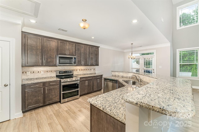 140 Wintergreen Ct, Lexington, NC 27295 - kitchen with appliances with stainless steel finishes, a sink, light wood-type flooring, dark brown cabinets, and tasteful backsplash