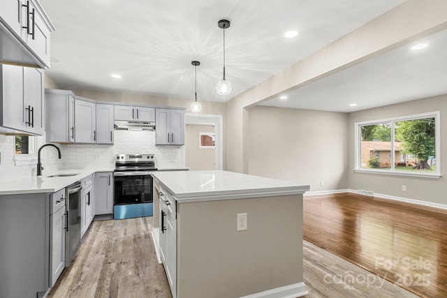 316 Fulton St, Kings Mountain, NC 28086 - kitchen with stainless steel appliances, a sink, gray cabinets, decorative backsplash, and light wood-style flooring