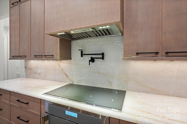78 Running Creek Trl Unit 93, Arden, NC 28704 - kitchen featuring oven, black electric cooktop, decorative backsplash, exhaust hood, and light stone countertops