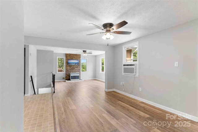 428 Jackson Rd, Fletcher, NC 28732 - unfurnished living room featuring a ceiling fan, light wood-type flooring, cooling unit, a textured ceiling, and baseboards