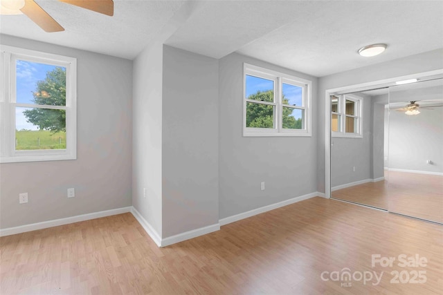 428 Jackson Rd, Fletcher, NC 28732 - unfurnished bedroom with multiple windows, light wood-style flooring, baseboards, and a textured ceiling