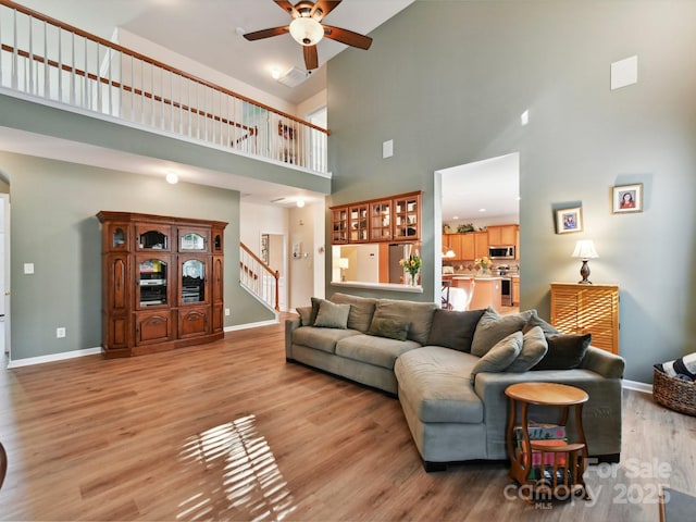 1564 Trippett St NW, Concord, NC 28027 - living room featuring a towering ceiling, a ceiling fan, stairs, light wood-type flooring, and baseboards