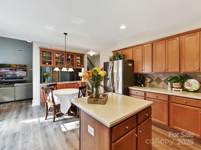 1564 Trippett St NW, Concord, NC 28027 - kitchen featuring stainless steel refrigerator with ice dispenser, glass insert cabinets, light countertops, brown cabinetry, and light wood-style floors