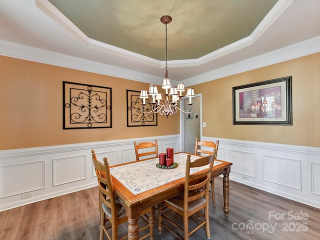 1564 Trippett St NW, Concord, NC 28027 - dining space with a raised ceiling, a chandelier, wood finished floors, a wainscoted wall, and crown molding