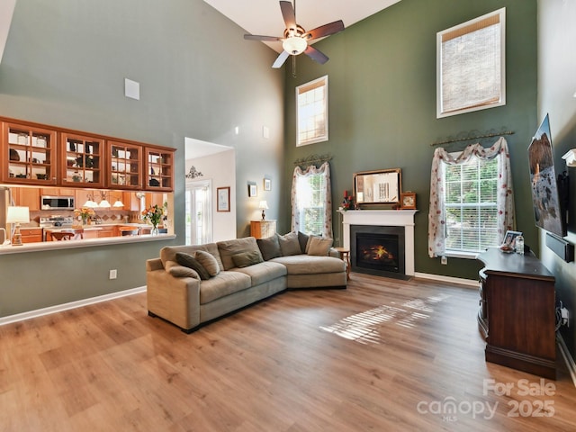1564 Trippett St NW, Concord, NC 28027 - living area featuring a towering ceiling, wood finished floors, a ceiling fan, a fireplace with flush hearth, and baseboards