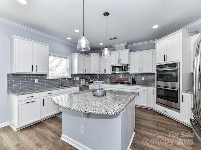 10800 Alabaster Dr, Davidson, NC 28036 - kitchen featuring appliances with stainless steel finishes, a sink, a kitchen island, white cabinetry, and crown molding