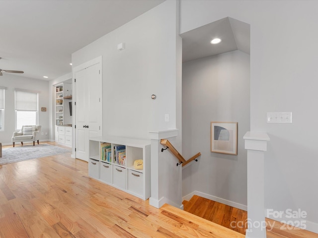 hallway with wood finished floors, baseboards, recessed lighting, and an upstairs landing