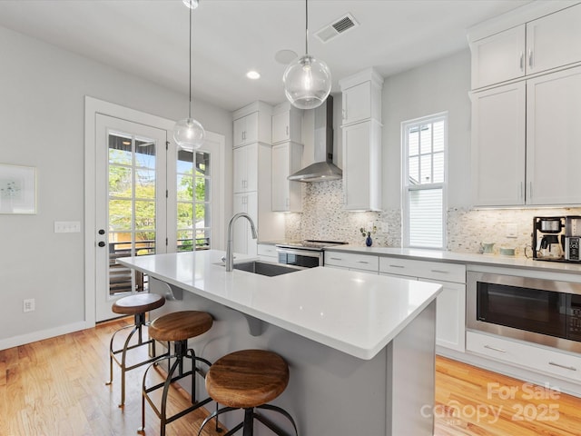kitchen featuring a sink, wall chimney exhaust hood, appliances with stainless steel finishes, healthy amount of natural light, and recessed lighting