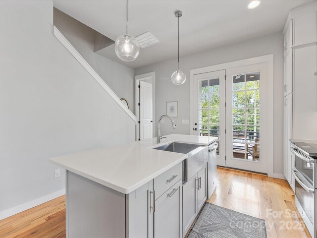 kitchen featuring a sink, stainless steel appliances, light wood-style floors, and baseboards