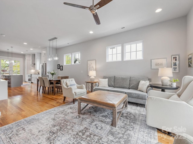 living room featuring healthy amount of natural light, ceiling fan, recessed lighting, and light wood-type flooring