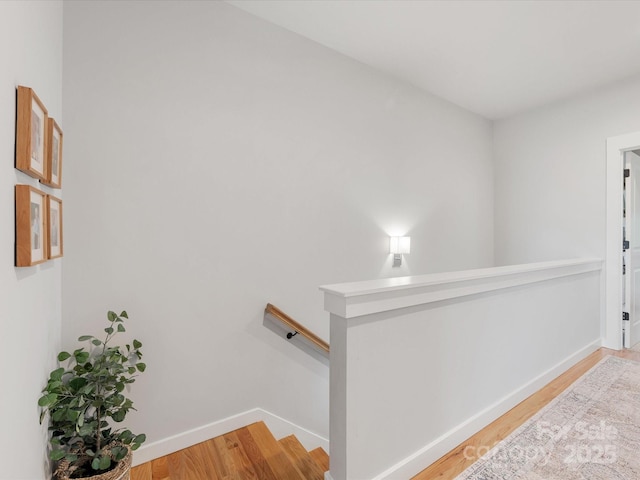 corridor with an upstairs landing, light wood finished floors, and baseboards