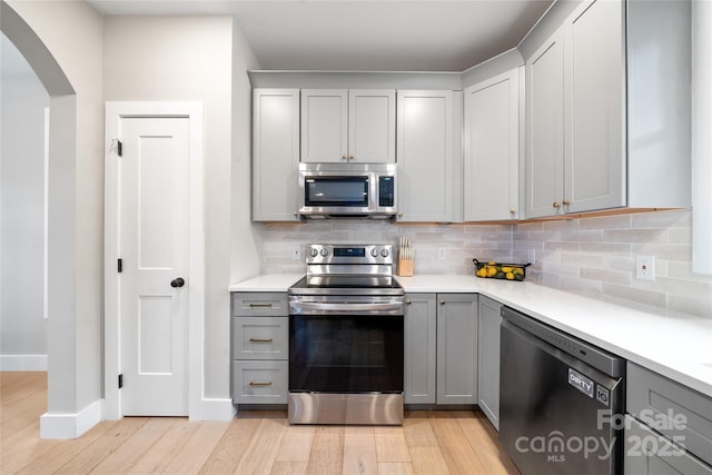 204 Maple Ave, Marion, NC 28752 - kitchen featuring stainless steel appliances, gray cabinetry, arched walkways, light wood finished floors, and light countertops