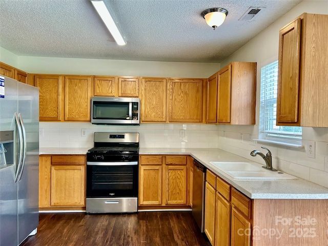 710 Woodington Ln, Charlotte, NC 28214 - kitchen featuring appliances with stainless steel finishes, a sink, light countertops, tasteful backsplash, and dark wood-type flooring