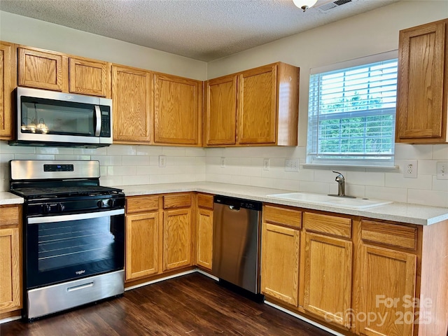 710 Woodington Ln, Charlotte, NC 28214 - kitchen featuring appliances with stainless steel finishes, a sink, decorative backsplash, dark wood-type flooring, and a textured ceiling