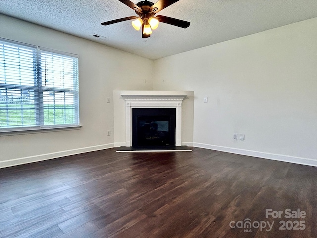710 Woodington Ln, Charlotte, NC 28214 - unfurnished living room with dark wood-type flooring, a ceiling fan, baseboards, a glass covered fireplace, and a textured ceiling