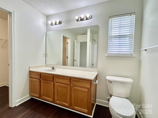 710 Woodington Ln, Charlotte, NC 28214 - bathroom featuring vanity, wood finished floors, a walk in closet, a textured ceiling, and toilet