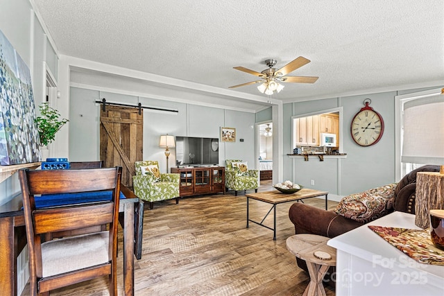 4920 Longfield St, Claremont, NC 28610 - living area featuring a barn door, ceiling fan, wood finished floors, a textured ceiling, and ornamental molding