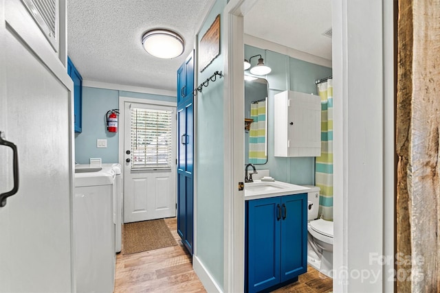 4920 Longfield St, Claremont, NC 28610 - full bath featuring washing machine and dryer, wood finished floors, toilet, vanity, and a textured ceiling