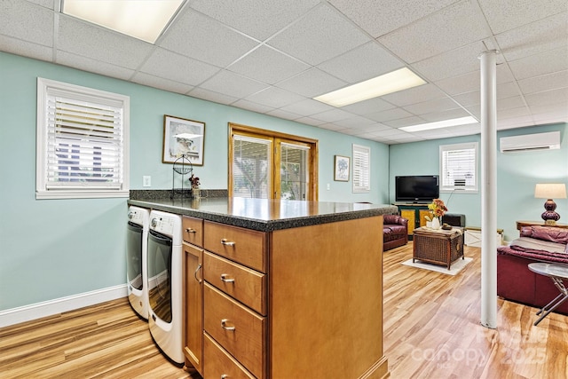 4920 Longfield St, Claremont, NC 28610 - kitchen featuring a wall mounted air conditioner, a peninsula, washer and clothes dryer, light wood-style floors, and brown cabinetry
