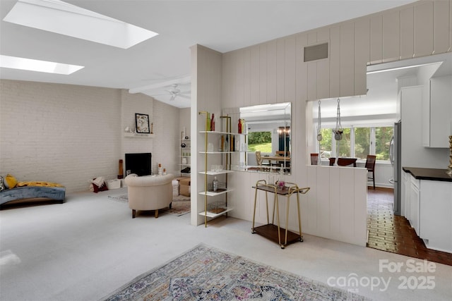 331 Glen Oaks Rd, Charlotte, NC 28270 - carpeted living area featuring brick wall, a skylight, vaulted ceiling, a brick fireplace, and a ceiling fan