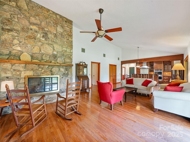 301 Fairway Ln, Spruce Pine, NC 28777 - living area featuring a stone fireplace, wood finished floors, ceiling fan, and high vaulted ceiling