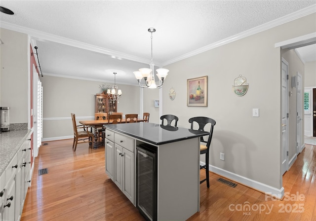 4101 Fairway Downs Ct Unit 9, Charlotte, NC 28277 - kitchen with beverage cooler, a breakfast bar area, light wood finished floors, crown molding, and a chandelier