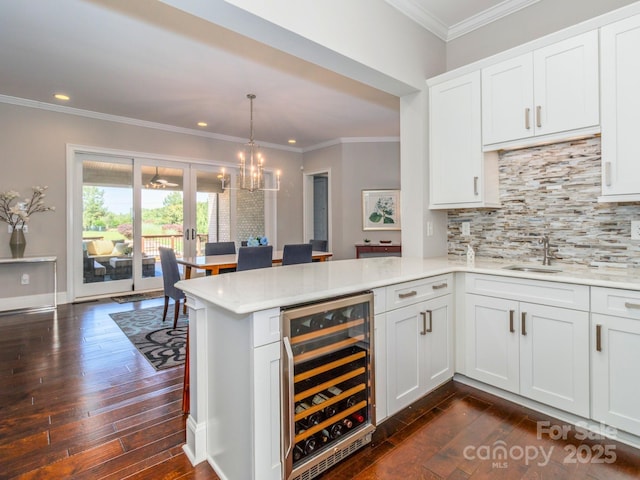 324 Squash Harvest Ct, Matthews, NC 28104 - kitchen with beverage cooler, a peninsula, dark wood-style flooring, tasteful backsplash, and ornamental molding