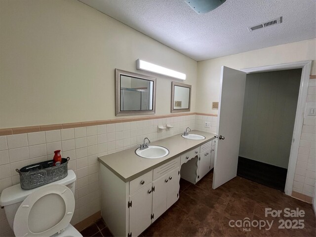 511 Evelyn Ave, Kannapolis, NC 28083 - full bath with tile walls, toilet, double vanity, a textured ceiling, and wainscoting